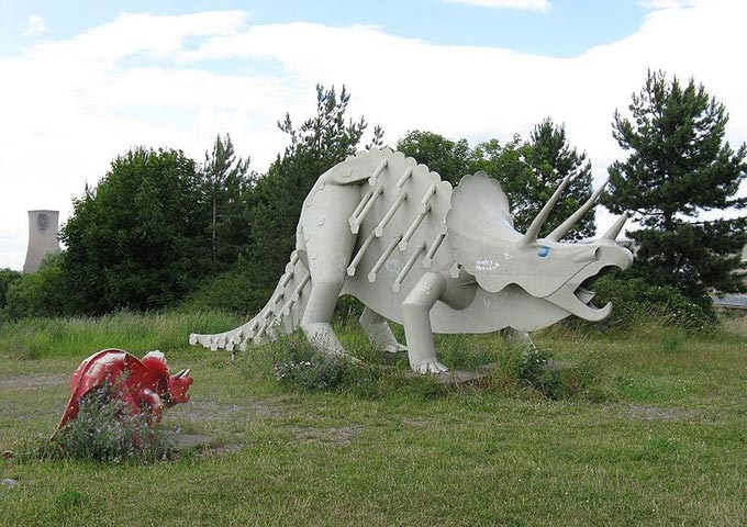 This picture shows a painted steel sculpture of a Triceratops dinosaur with its baby close by.