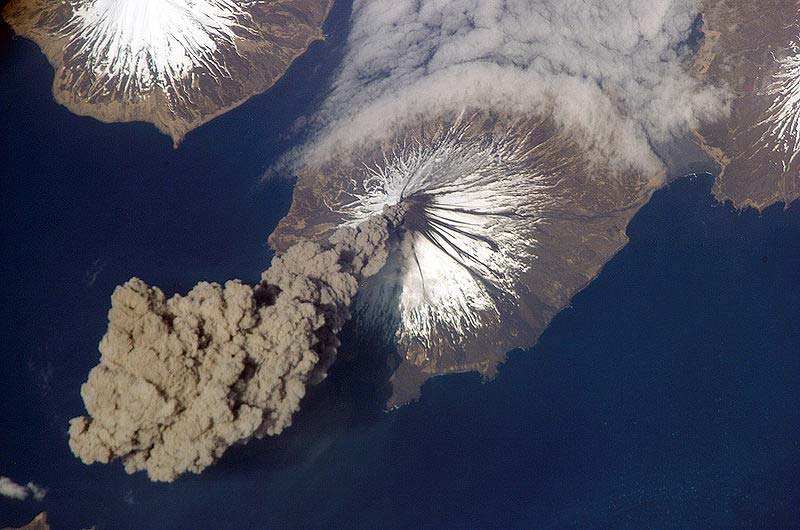 This amazing photo shows a volcanic eruption as seen from space. A giant plume of smoke bellows out from the ice capped volcanic crater.