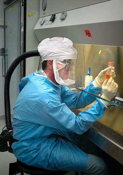 This photo shows a medical scientist hard at work doing research in a laboratory. He is wearing a range of protective clothing and equipment to ensure his safety around hazardous substances.