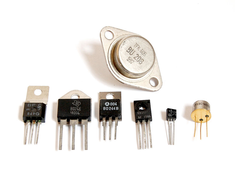 This photo shows a close up of seven different transistor types set against a white background.