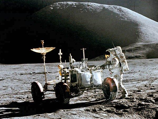 A photo of an astronaut as he interacts with a lunar rover while on the moon.