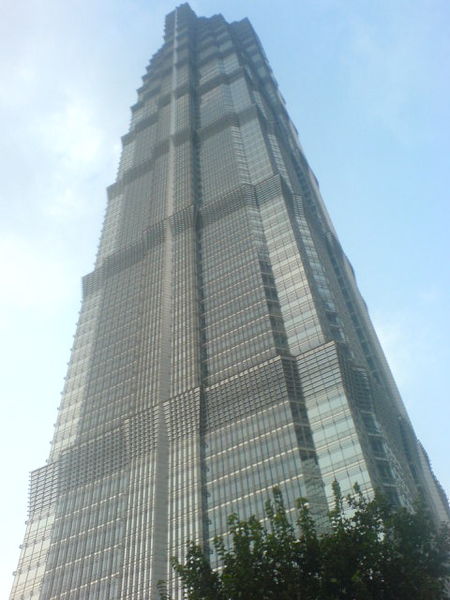 This is a photo of the Jin Mao Tower in Shanghai, China. The massive skyscraper is one of the tallest buildings in the world, featuring 88 floors. Opened in 1998, it stands 421 metres in height (1380 feet). The image is taken from the ground and looks up towards they sky as the tower rises above.