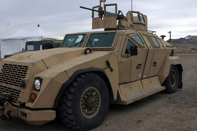This photo shows a US Army Tactical Combat Vehicle. The Combat Vehicle is heavily armored, has huge wheels and is equipped with weapons.