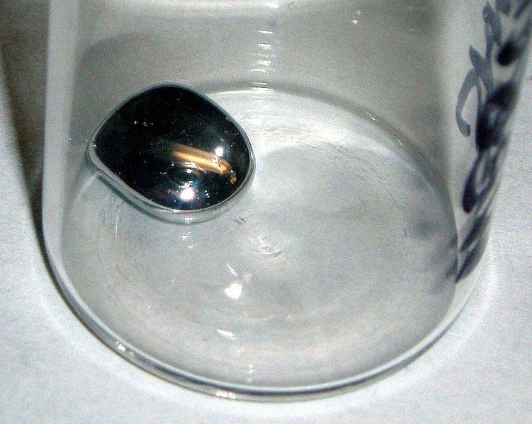 A close up photo showing a blob of mercury sitting safely inside a glass container. At room temperature this metal is in liquid form, the liquid metal moving around like something out of the movie Terminator 2 Judgment Day. Mercury can be toxic when held against the skin, something that was not known in the past.