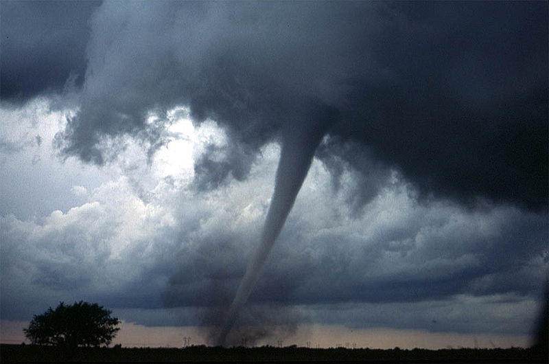 A huge tornado in Oklahoma, USA plows its way through anything standing in its path. It whips up debri from the ground below while the storm rages on in the dark skies above.