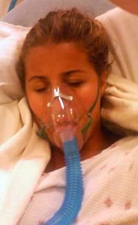 This photo shows a patient wearing an oxygen mask while lying on a hospital bed.