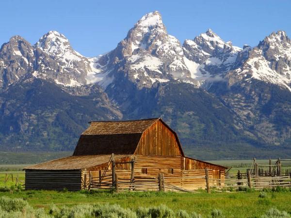 This photo features a wooden barn in the foreground and Grand Teton in the background. Grand Teton is the highest mountain in Grand Teton National Park, Wyoming, USA.
