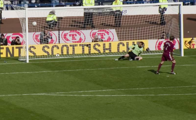 A photo taken just moments after a football player successfully scored a goal from a penalty kick, deceiving the goalkeeper and sending him in the wrong direction.