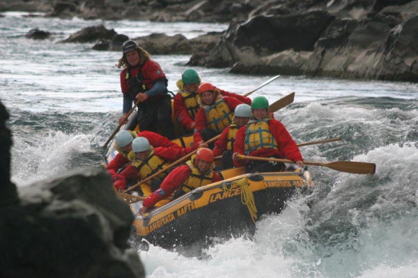 A group of rafters head down the rapids of a river used for white water rafting.