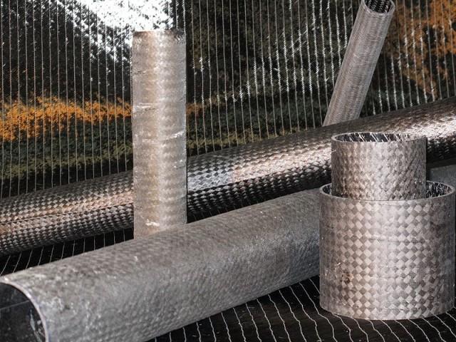 Carbon fibre samples in a range of shapes and size sit on a mat. Most are hollow and feature a cylindrical shape.
